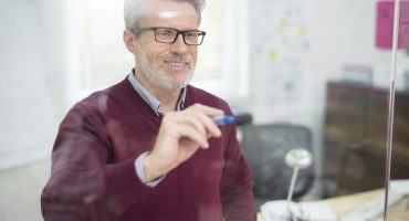 Man using glass wall to write some information