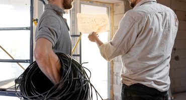 Two builders look at the drawing of the object