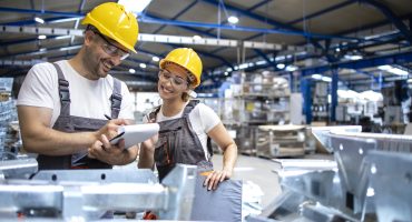 Factory workers checking quality of products in large industrial hall.