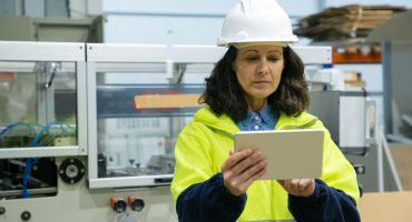 Focused female industrial worker using tablet computer onsite