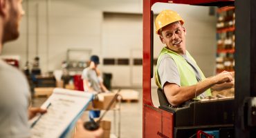 Happy forklift operator talking with a foreman while working in