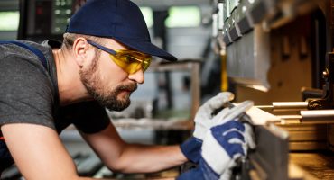Portrait of worker near metalworking machine, steel factory background.