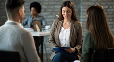 Happy financial advisor having an interview with a couple in the office.