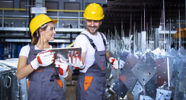 Factory workers working together in industrial metal production line.